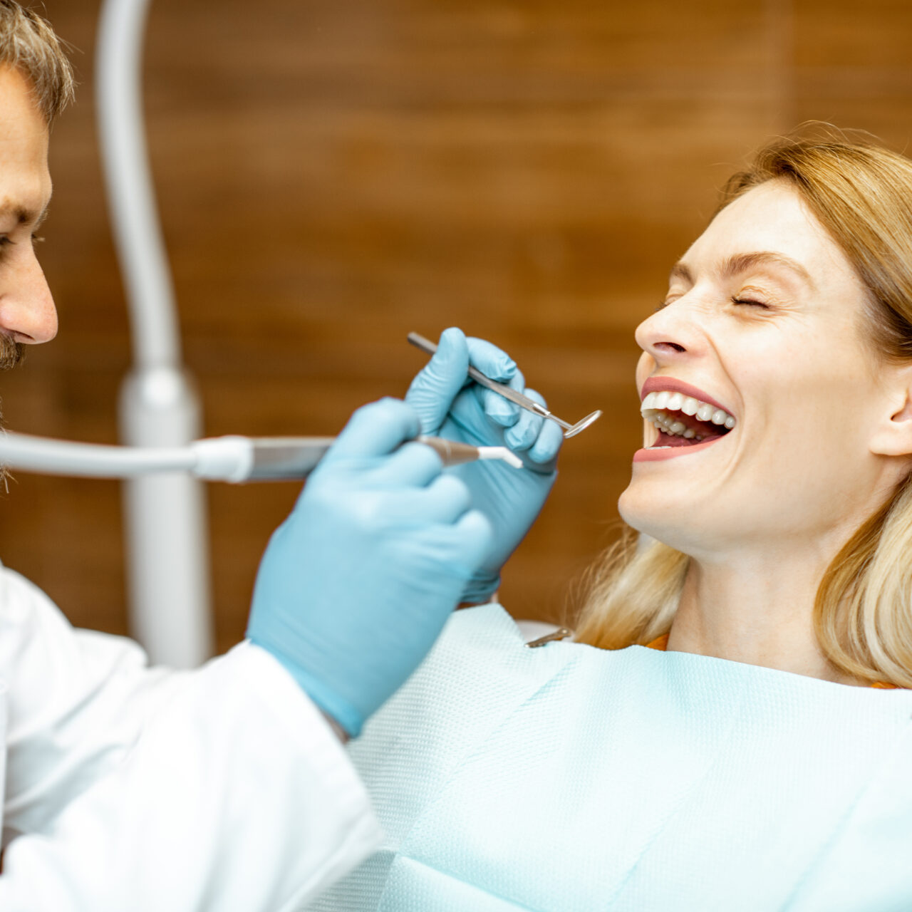 Beautiful woman as a patient with senior dentist smiling and feeling trust during a medical consultation at the dental office
