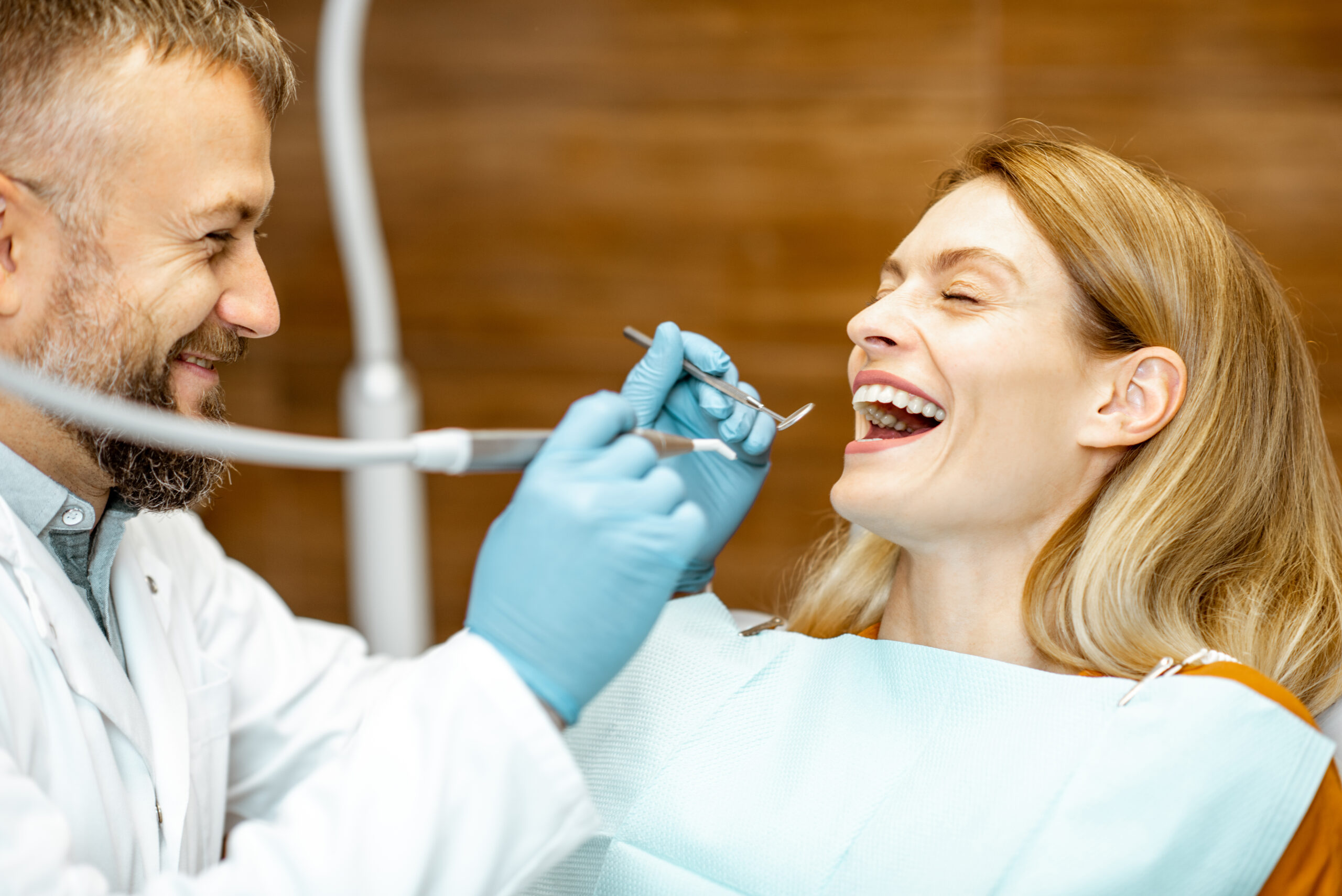 Beautiful woman as a patient with senior dentist smiling and feeling trust during a medical consultation at the dental office